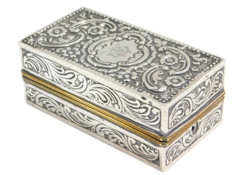 A Victorian silver and brass rectangular box, decorated with rococo scroll flower heads surrounding a central cartouche with monogram, London 1890, 6.32oz all in, 10cm long.