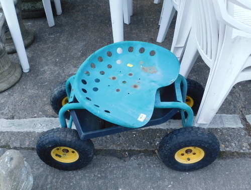 A small four wheel gardening truck, with a green painted metal seat.