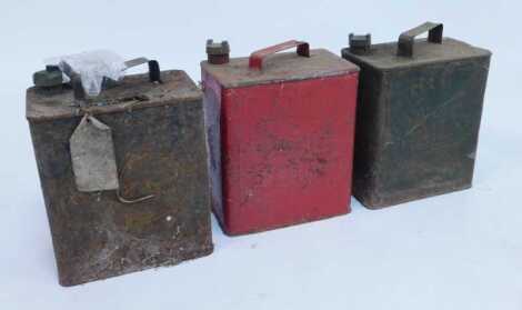 Three metal fuel cans including a Pratts fuel can, in red, green and black.