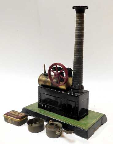 An early 20thC Bing German tinplate static engine, with brass boiler, simulated tile base and chimney, stamped to boiler and to side, 25cm wide.