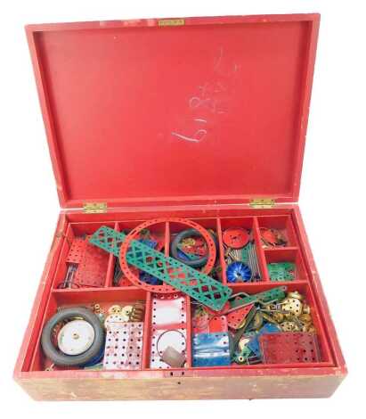 Meccano, contained in a sign written red painted case, the hinged lid enclosing two layers with various sections for Meccano, 51cm wide.