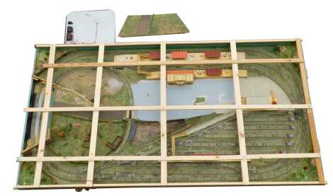 A Hornby Dublo three rail layout, comprising Hornby Dublo D1 station buildings, D1 level crossing, D1 footbridge, point switches, etc., 236cm long, 123cm wide, 15cm deep.