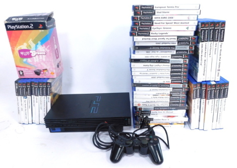 A Playstation 2 console, games and accessories, including Eye Toy Groove, International Tennis Pro, Pro Evolution Soccer Six, Midnight Club 2, and controllers.