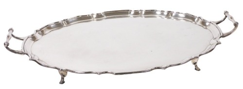 A George V silver oval two-handled tray, with Chippendale style border and scrolling handles, raised on four stylised hoof feet, Birmingham 1929, 56oz, 52cm wide,.