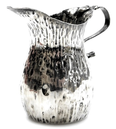 A Victorian silver Arts and Crafts cream jug, of hammered design with arched handle, maker W J H, Birmingham 1898, 2.30oz