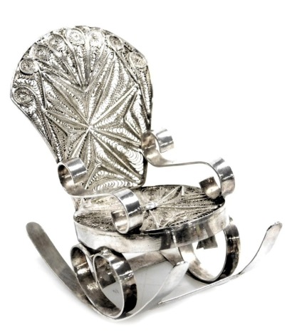 A Continental white metal miniature rocking chair, with filigree scroll patterning, on stout base, maker F G K, 1.24oz.