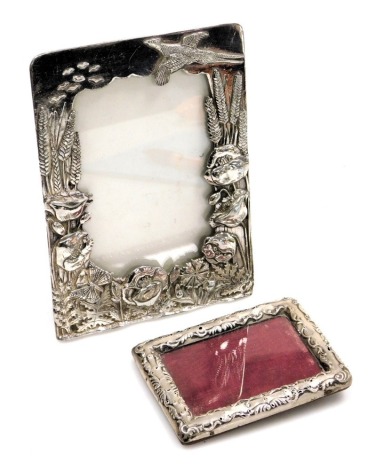 Two photograph frames, comprising a Victorian silver photograph frame of rectangular form, with scroll border and rubbed hallmarks, 12cm x 8cm, and a silver plated copy Silver Scene frame. (2)