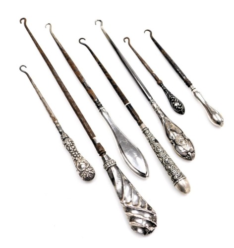 Seven white metal handled Victorian and later button hooks, comprising two of plain design, the others of twist or foliate design, each with a stainless steel hook, some with rubbed marks, some unmarked. (AF)