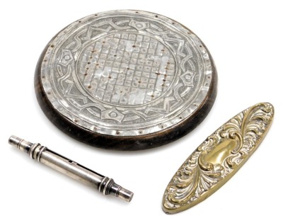 A group of silver and other vertu, comprising a hammered coaster, on wooden base, with raised design, 14cm wide, a brass dressing table lid, 14cm wide, and a silver plated cigar holder. (3)