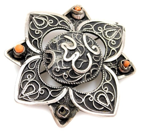 A Middle Eastern star design brooch, with raised scroll detail, set with coral, 6cm wide, white metal unmarked, 18.5g all in.