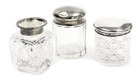 Three cut glass and silver topped dressing table jars, comprising two circular examples, a silver plated topped inkwell. (3)