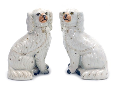 A pair of Victorian Staffordshire pottery King Charles spaniel comforter dogs, with free standing front feet. painted muzzles and highlighted in gilt, 25cm high.