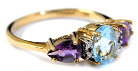 A 9ct gold aquamarine and amethyst three stone ring, with pairs of diamonds at intervals, the oval cut aquamarine flanked by two pear shaped amethysts, size O, 2.3g.