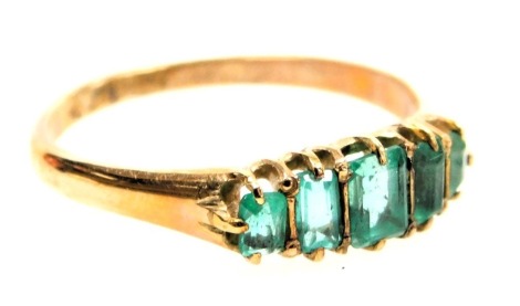 An emerald five stone ring, set with five graduated baguette cut stones, in yellow metal, unmarked, size Q, 2.5g.