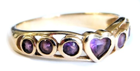 A 9ct gold and amethyst seven stone ring, with a central heart shaped setting, flanked by three circular settings, size O, 2.6g.