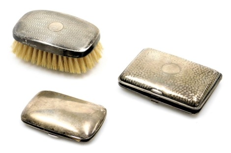 A George V silver cigarette case, with mottled decoration, circular vacant reserve, Birmingham 1918, Victorian silver cigarette case, further cigarette case, Birmingham, 3.22oz, together with a George V silver backed hairbrush, with engine turned decorati