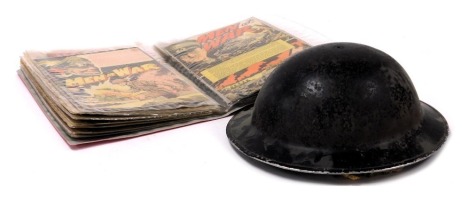 A World War II British Civil Defence helmet, together with an album of World War II related comic pages. (2)