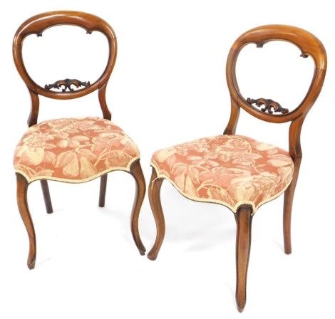 A pair of Victorian mahogany balloon back dining chairs, with overstuffed red and cream floral upholstery, raised on cabriole legs.