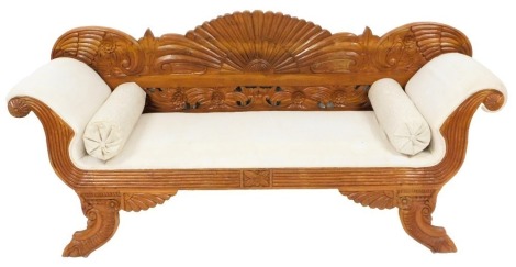 A Regency style hardwood sofa, with a carved floral back, scrolling arms, raised on outswept feet, with scatter cushions and bolsters, 196cm wide.