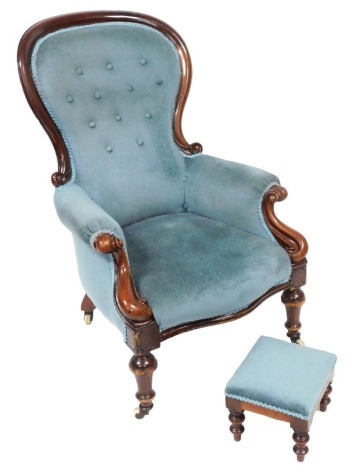 A Victorian mahogany balloon back armchair, upholstered in button back light blue draylon raised on turned legs, brass capped on castors, 71cm high, together with a footstool, upholstered in the same fabric, 26.5cm wide. (2)