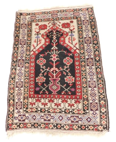 A Caucasian prayer rug, the mihrab filled with an urn and tree of life, against a cream ground, with flowers within repeating geometric borders, 122cm x 83cm.