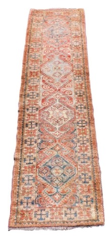 A Kurdistan red ground runner, decorated with four central medallions, within repeating floral and dogtooth borders, 286cm x 82cm.