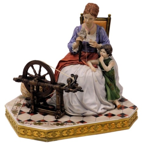 A Capodimonte porcelain figure group, modelled as seated lady at a spinning wheel, child at her side, by Sandro Maggiori, printed mark, 30.5cm wide.