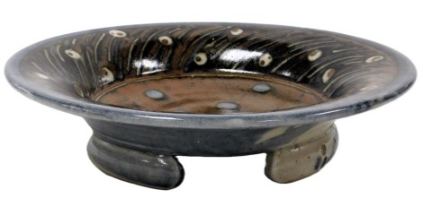 A David Frith studio pottery bowl, of circular form, decorated with white circles against a brown ground, within a feathered border, seal mark, bears label, 32cm wide.