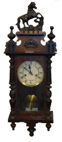 A late 19thC Continental pine cased wall clock, circular brass dial with chapter ring bearing Roman numerals, eight day movement, the case with a shaped pediment surmounted by a rearing horse, above a glazed door flanked by turned demi pilasters, 73cm hig