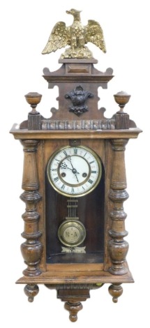 A late 19thC Continental oak cased wall clock, circular brass dial with enamel chapter ring bearing Roman numerals, eight day movement, the case with shaped pediment surmounted by a gilded eagle, above a glazed door flanked by turned demi pilasters, with 