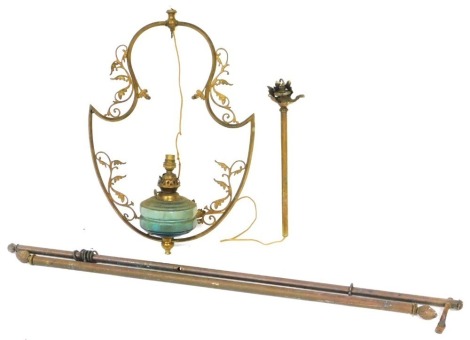 A Victorian brass hanging oil lamp, with a lyre and foliate scroll brass frame, the lamp with a faceted green glass reservoir, 101cm high, and two brass curtain poles. (3)