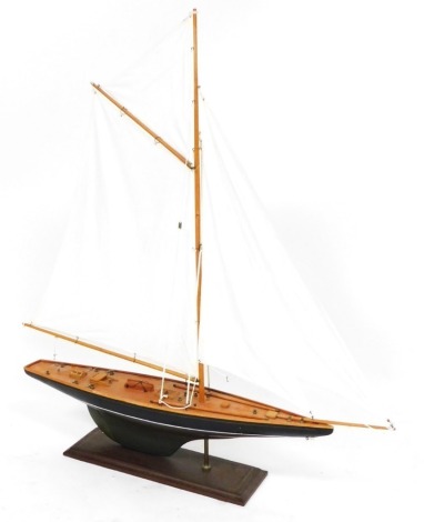 A wooden scale model of a racing yacht, rigged and in full sail, raised on a wooden stand, 100cm high.