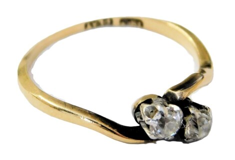 A diamond two stone ring, in a crossover design, in white and yellow metal, stamped 18ct and plat, approx ¼ct, size L/M, 1.8g.