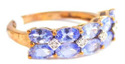 A tanzanite and diamond dress ring, set with eight oval cut tanzanite's and four tiny diamonds, each in a claw and illusion setting, on a yellow metal band stamped 9kt, ring size O, 2.5g all in, boxed.