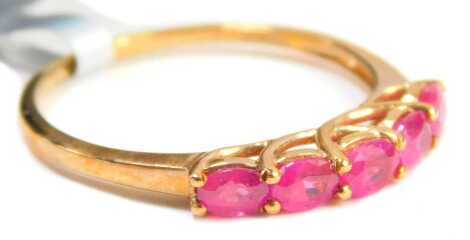 A ruby dress ring, set with five oval cut rubies, each in a claw setting, on a hooped over shank, yellow metal stamped 9kt, ring size S, 1.7g all in, boxed.