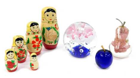 A group of glassware, comprising a globular paperweight with pink floral and bubble decoration, 15cm high, pear-shaped paperweight, 14cm high, a blue glass apple paperweight, 6cm high, and a set of five Matryoshka nesting dolls.