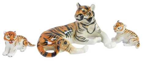 A Russian porcelain figure modelled as a seated tiger, 18cm high, and two cubs, each 10cm high, printed marks.