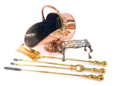 A copper helmet shaped coal scuttle, with ring handle, 39cm long, together with a cast iron trivet, and three brass fireside implements, comprising poker, tongs and shovel.