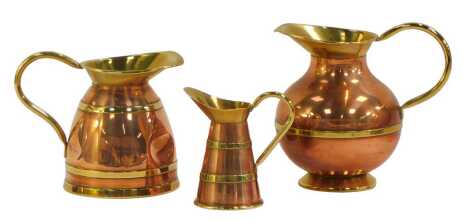 Three copper and brass bound jugs, each of varying design, the largest 16.5cm high.