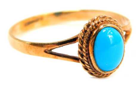 A 9ct gold and turquoise dress ring, the oval turquoise in a rope twist border, on V splayed shoulders, ring size Q½, 1.6g all in.