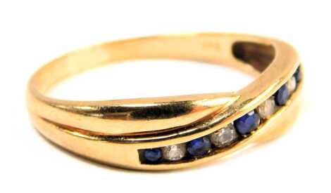 A sapphire and diamond cross over ring, set with five sapphires and four tension set diamonds, yellow metal stamped 375, size P½, 2.1g all in.