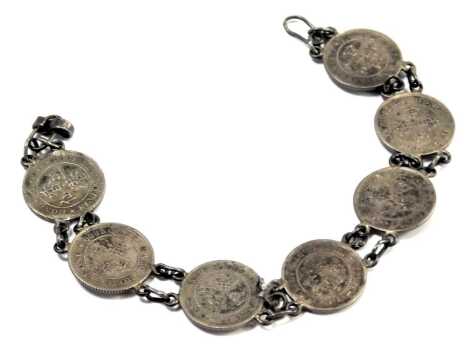 A silver sixpence coin bracelet, set with seven silver coins, each with white metal chain links, 16cm long, 12g.