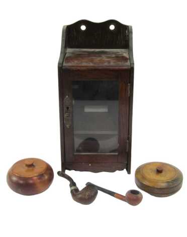 An early 20thC oak smoker's cabinet, the raised gallery top with a hinged lid, the front with a glazed door enclosing a recess with yew wood jar and pipe with drawer to base containing a further tobacco jar and two pipes, 30cm high.