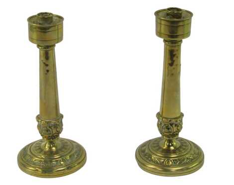 A pair of early 20thC brass candlesticks, each with an embossed leaf and roundel circular base, 25cm high.