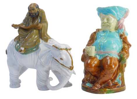 A Chinese Wang Tang pottery figure depicting an man reading a scroll on an elephant, 27cm high, together with a Majolica pottery character jug modelled as Sir John Falstaff, seated holding beer stein, 26cm high.