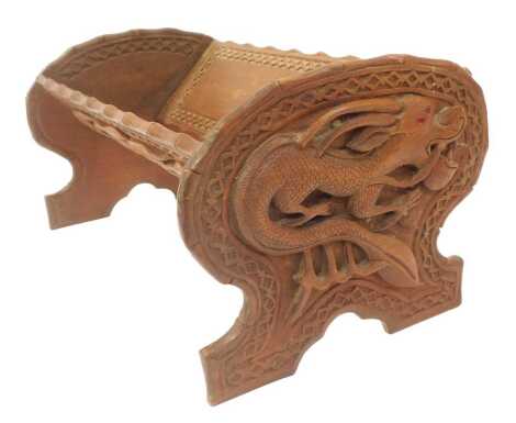 An Oriental style carved book trough, each end decorated with a dragon with coloured stone inset eyes, 33cm wide.