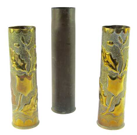 Trench Art. Two shell cases converted to vases, embossed with shields, acorns and oak leaves, on a hammered ground, 30cm high, together with a further undecorated shell case, 34cm high. (3)