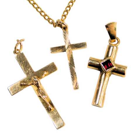 Three crucifix pendants, comprising a 9ct gold example with a raised figure, a garnet set crucifix, bearing full UK hallmarks for 9ct, and a further example on a plated chain, the crucifixes 4.1g all in. (3)