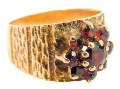 A garnet dress ring, the garnet floral cluster in a claw setting, with bark effect design shoulders and setting, yellow metal stamped 9ct, ring size O½, 4.1g.