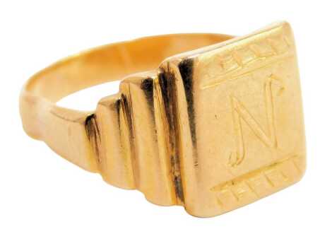 A signet ring, the square set panel bearing the initial N, on three layered staggered sides in the Art Deco style, yellow metal stamped 18ct, ring size I½, misshapen, 4.3g.